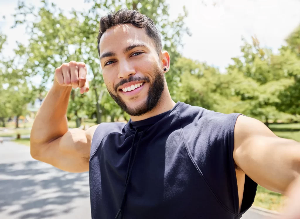 smiling man flexing muscles in outdoor setting utc